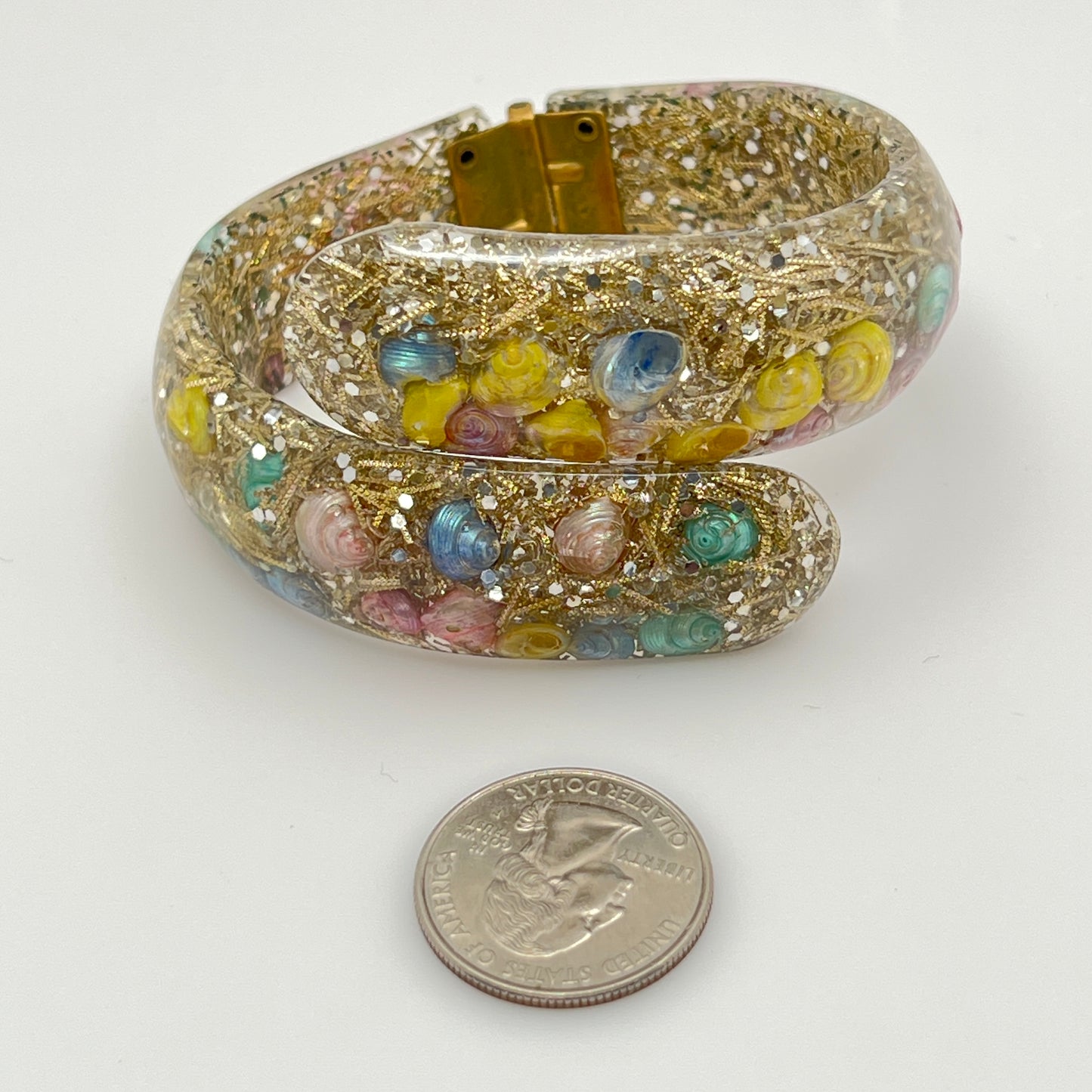 Vintage hinged bracelet with colorful shells suspended in clear lucite