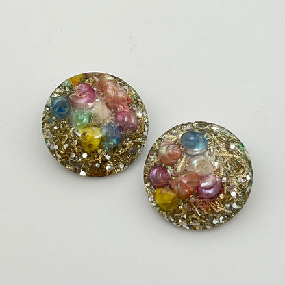 Close-up of lucite earrings with multicolor seashells and gold sparkle