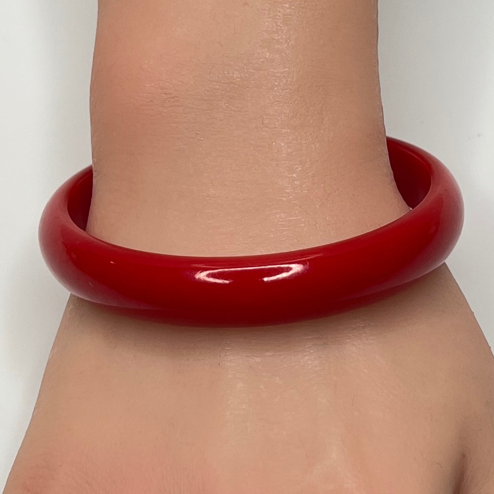 Vintage red Bakelite bangle bracelet on wrist, glossy finish