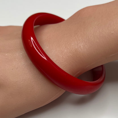 Vintage red Bakelite bangle bracelet on wrist, glossy finish