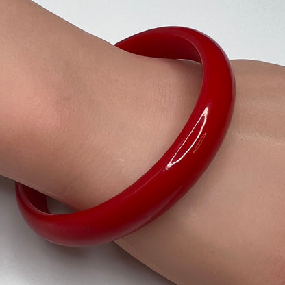 Vintage red Bakelite bangle bracelet on wrist, glossy finish