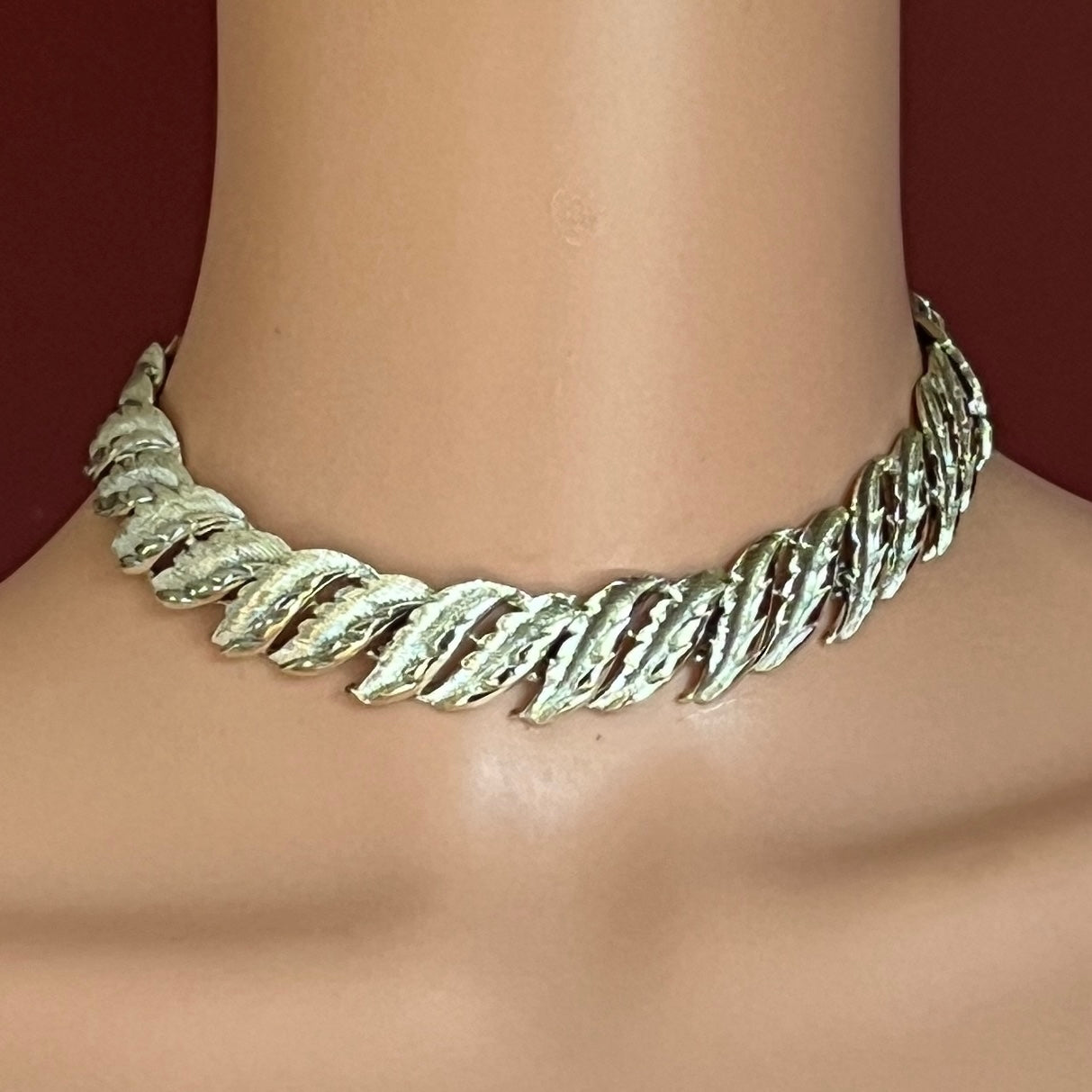 Silver leaf-patterned necklace on a mannequin with a dark background