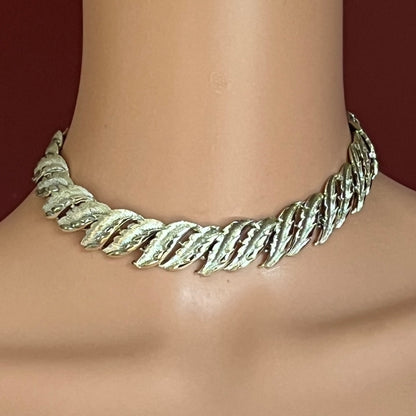 Silver leaf-patterned necklace on a mannequin with a dark background