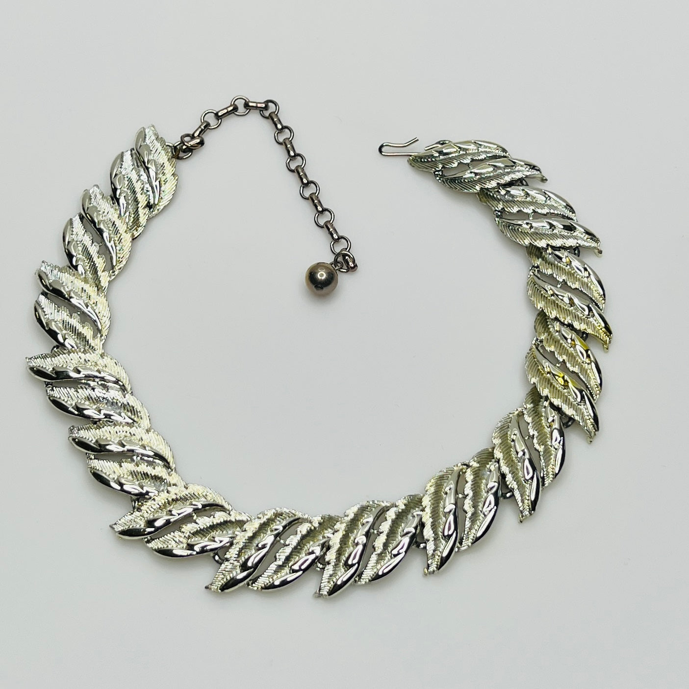 Mid-century silver-tone choker necklace with sculpted leaf links and hook extender clasp.
