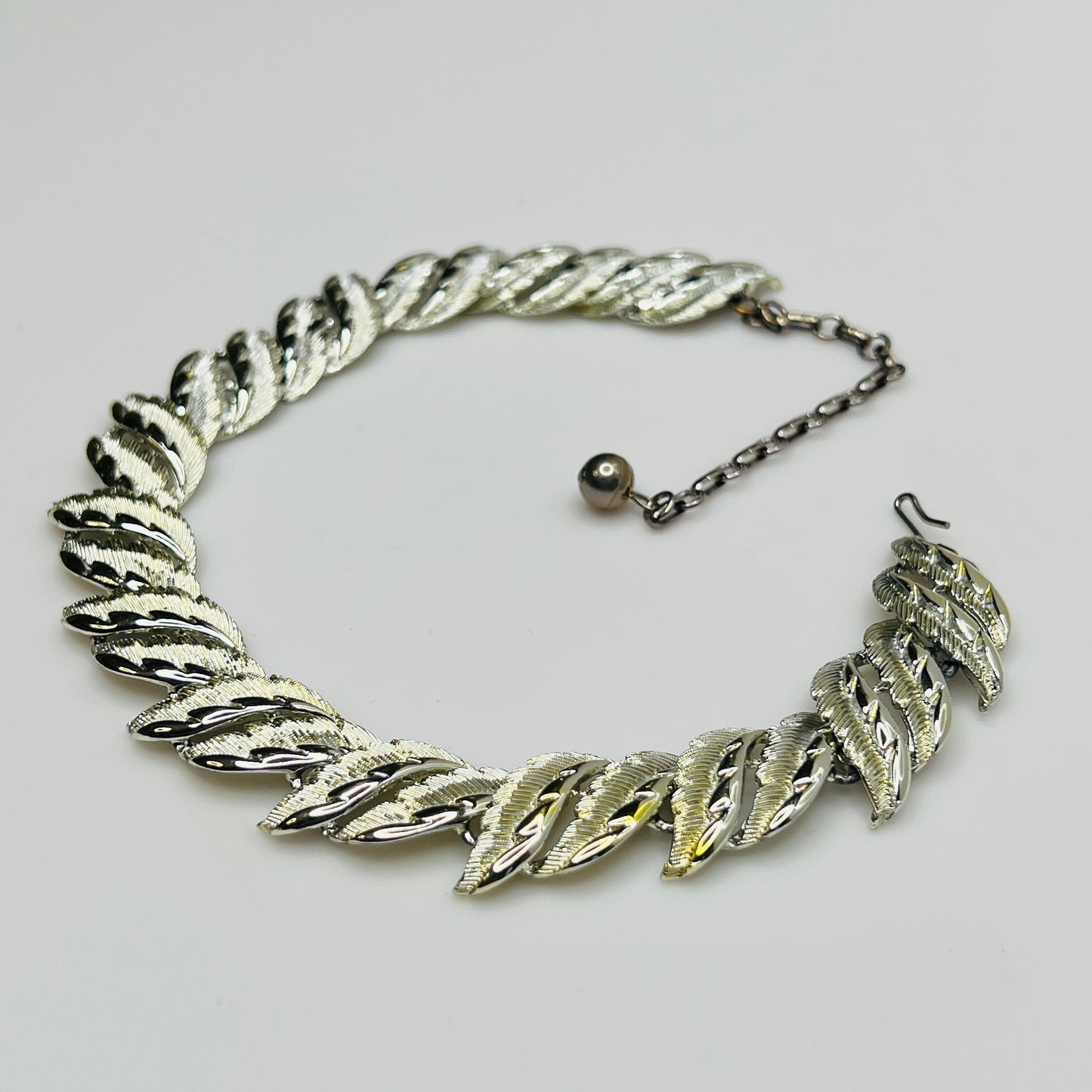Mid-century silver-tone choker necklace with sculpted leaf links and hook extender clasp.