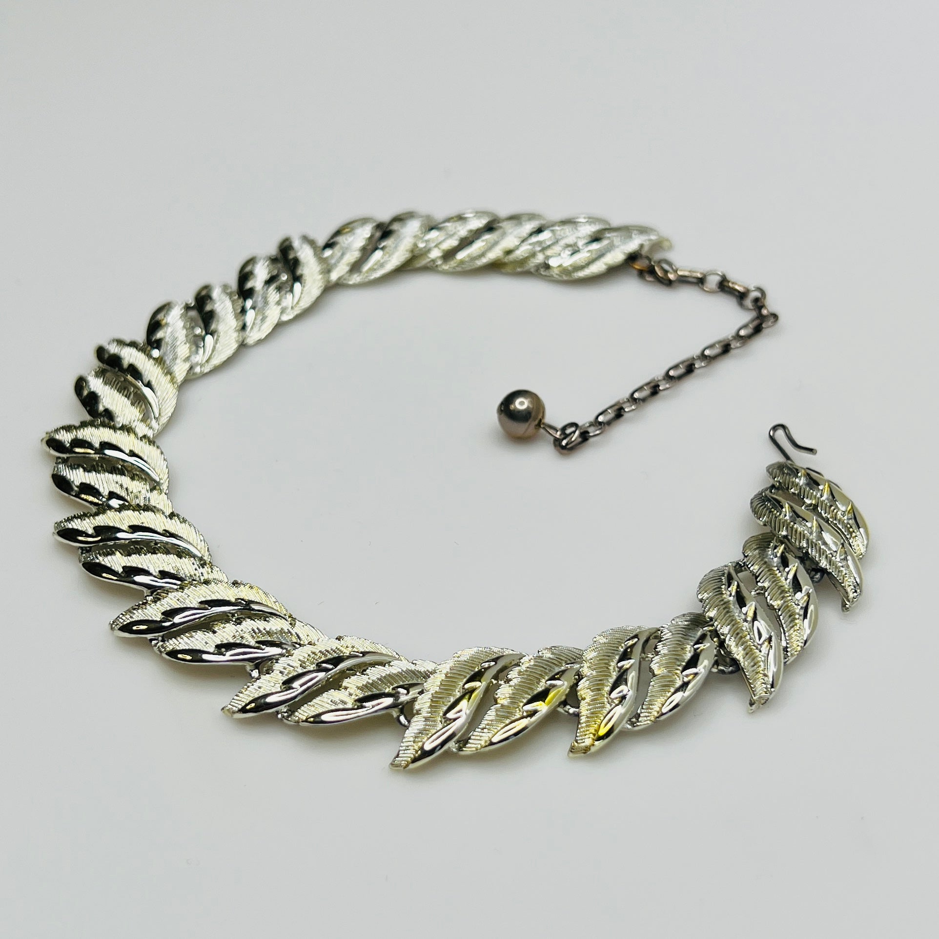 Mid-century silver-tone choker necklace with sculpted leaf links and hook extender clasp.
