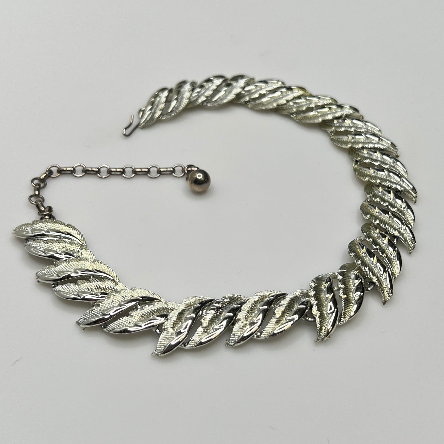Mid-century silver-tone choker necklace with sculpted leaf links and hook extender clasp.