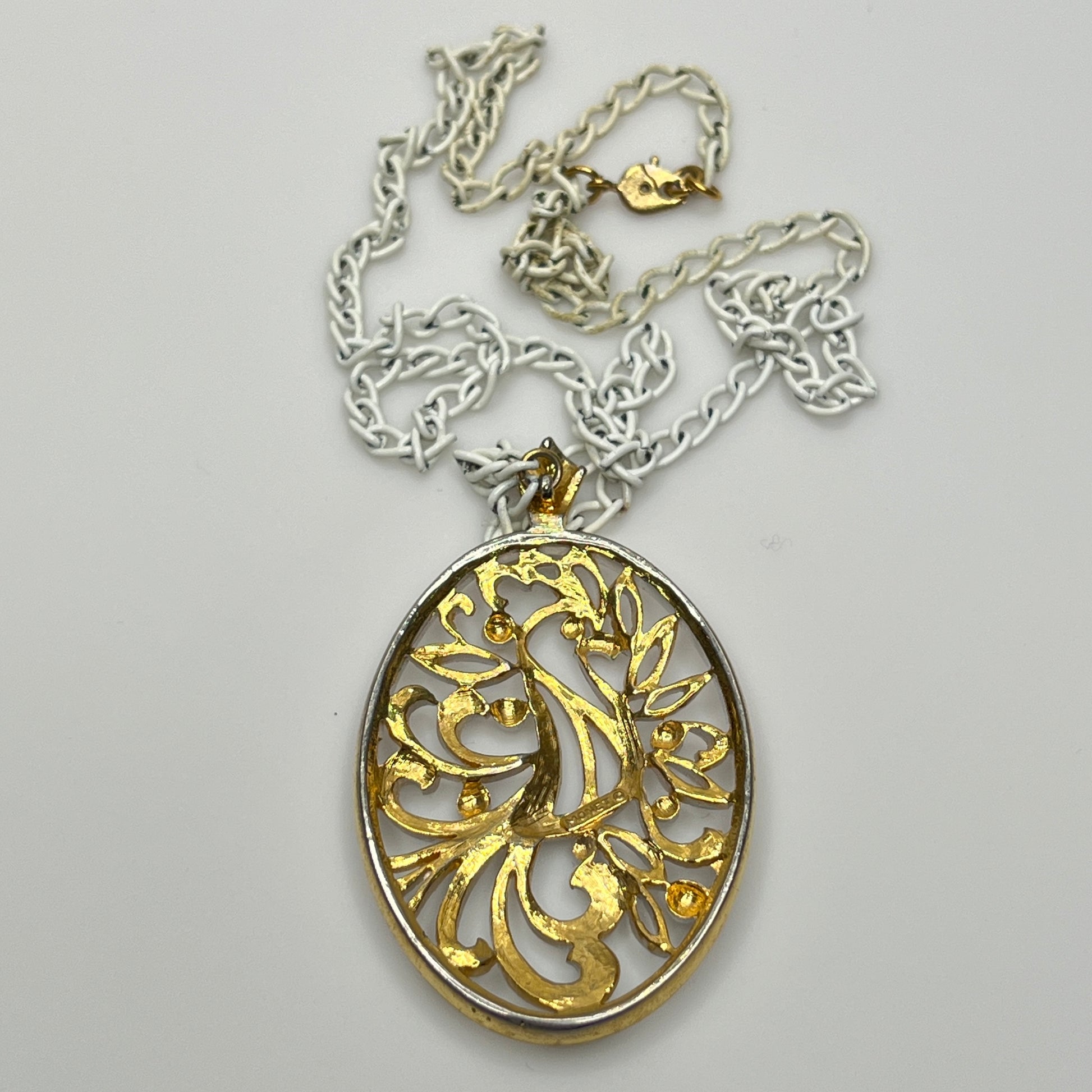 Close-up of pendant and chain showing vintage wear on enamel near clasp