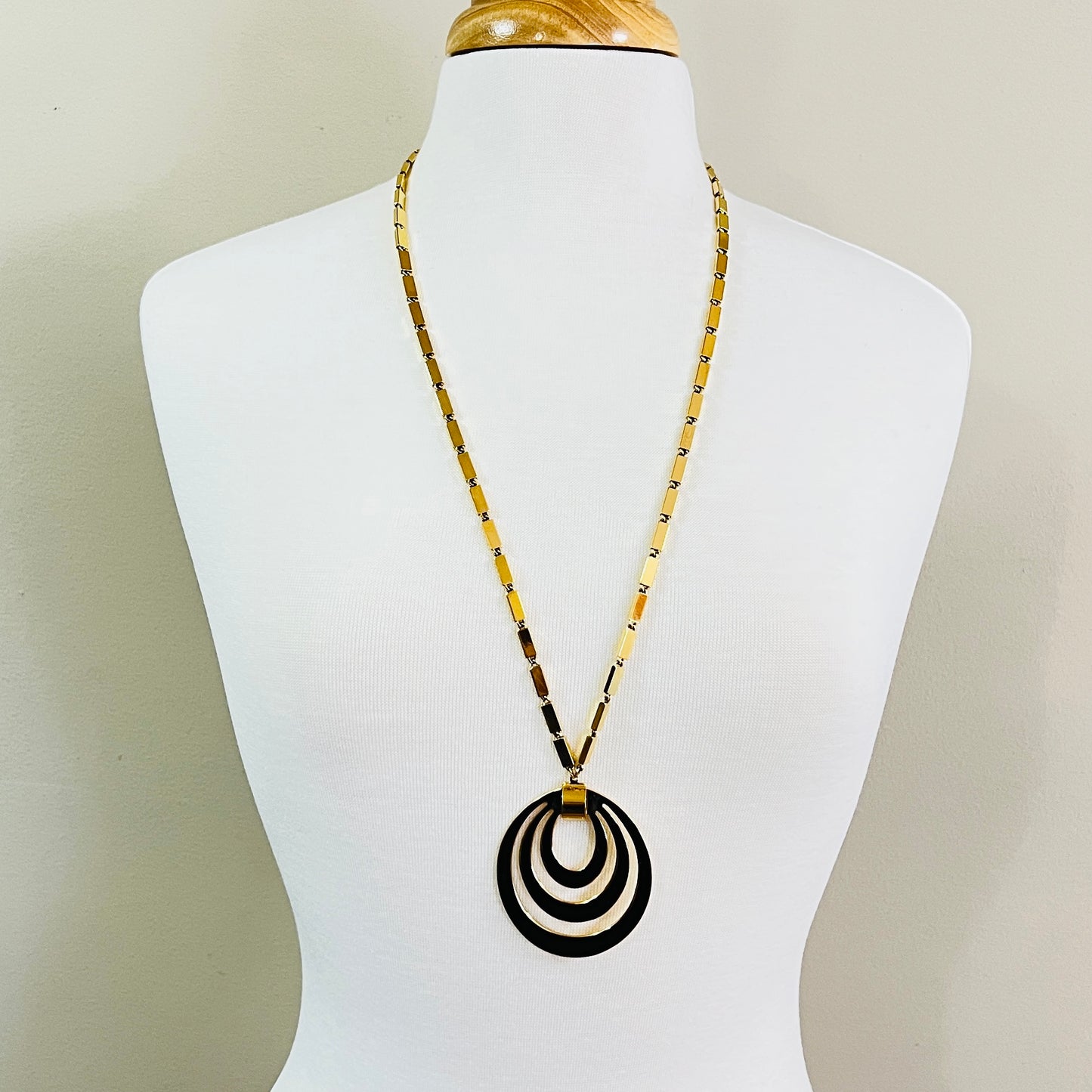 Vintage Monet goldtone pendant necklace on display bust, featuring concentric oval drop