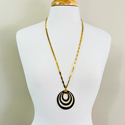 Vintage Monet goldtone pendant necklace on display bust, featuring concentric oval drop