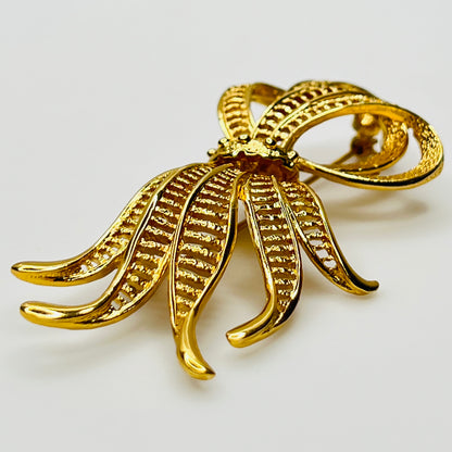 Side view of dimensional gold ribbon brooch with textured detailing