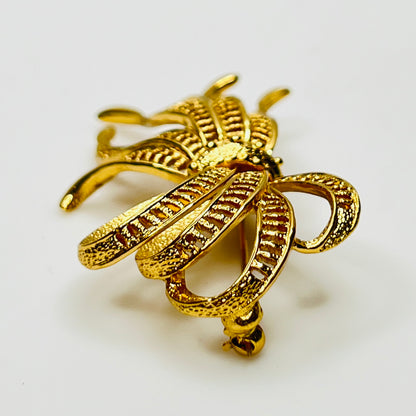 Side view of dimensional gold ribbon brooch with textured detailing