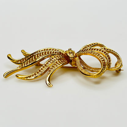 Side view of dimensional gold ribbon brooch with textured detailing
