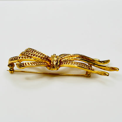 Side view of dimensional gold ribbon brooch with textured detailing