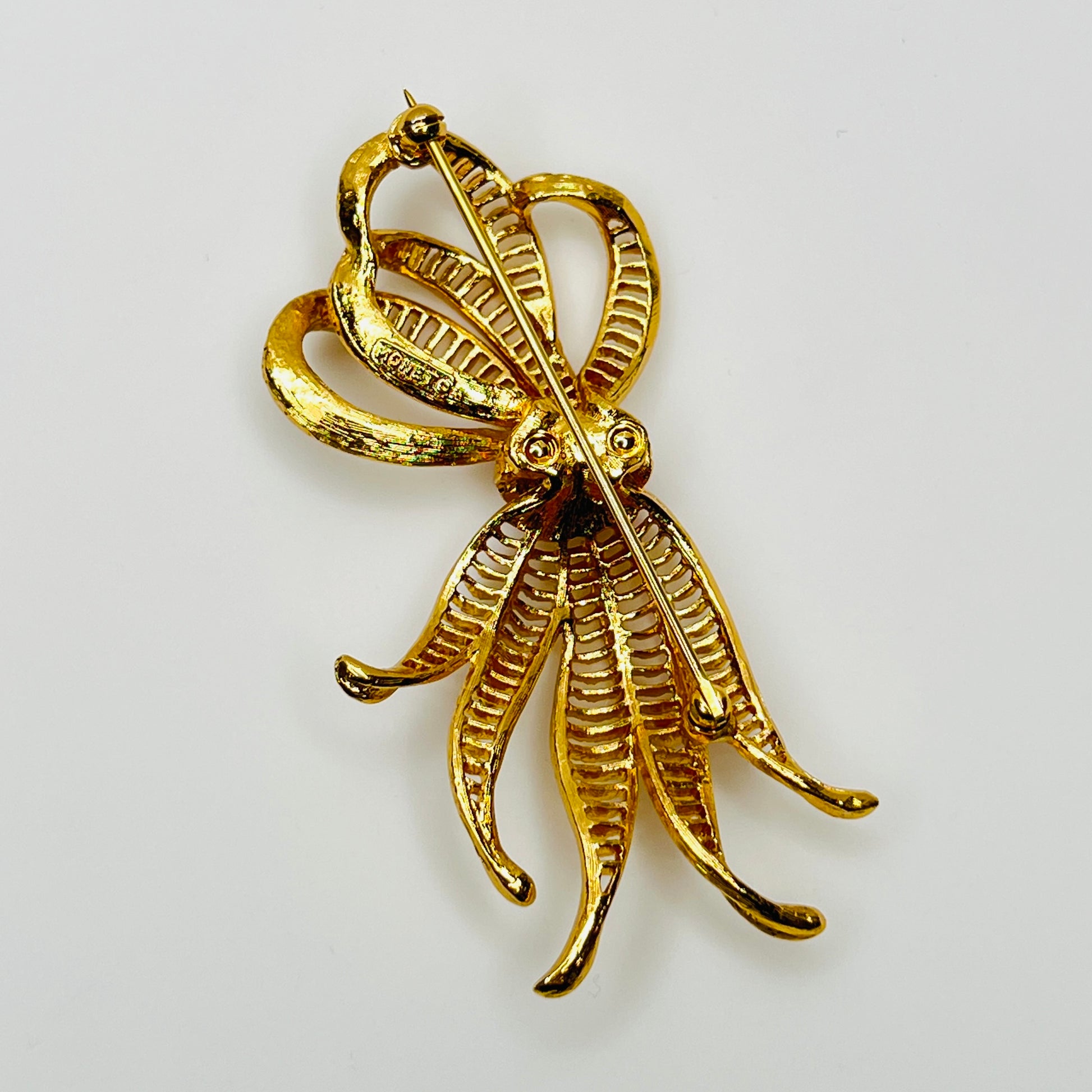 back view of dimensional gold ribbon brooch with textured detailing