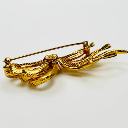 Side view of dimensional gold ribbon brooch with textured detailing