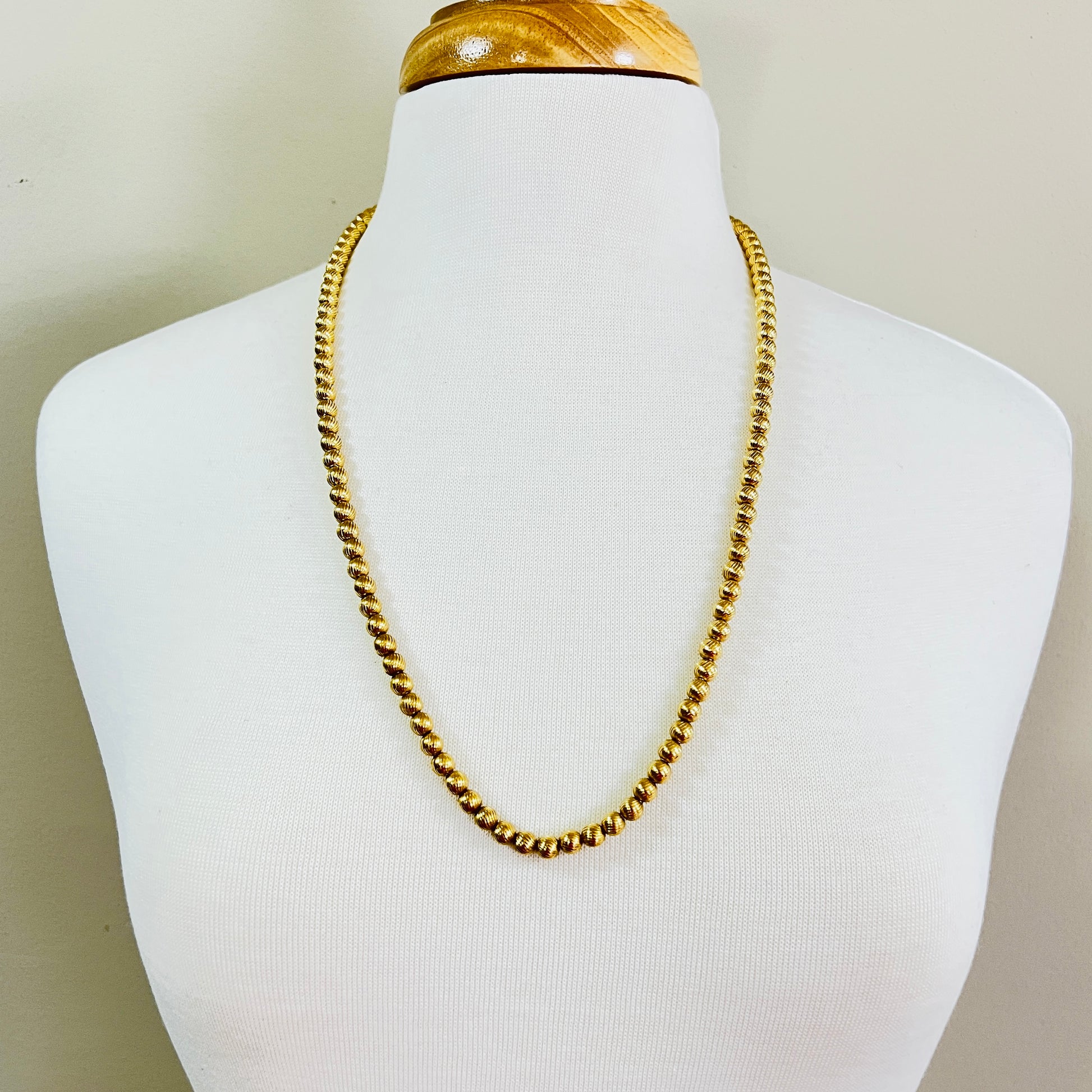 Gold bead Monet necklace displayed on mannequin opera length