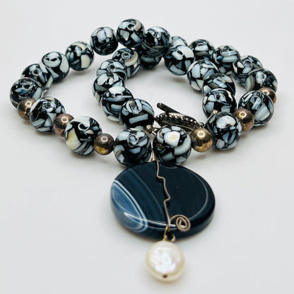 Centered view of striped agate pendant with pearl drop
