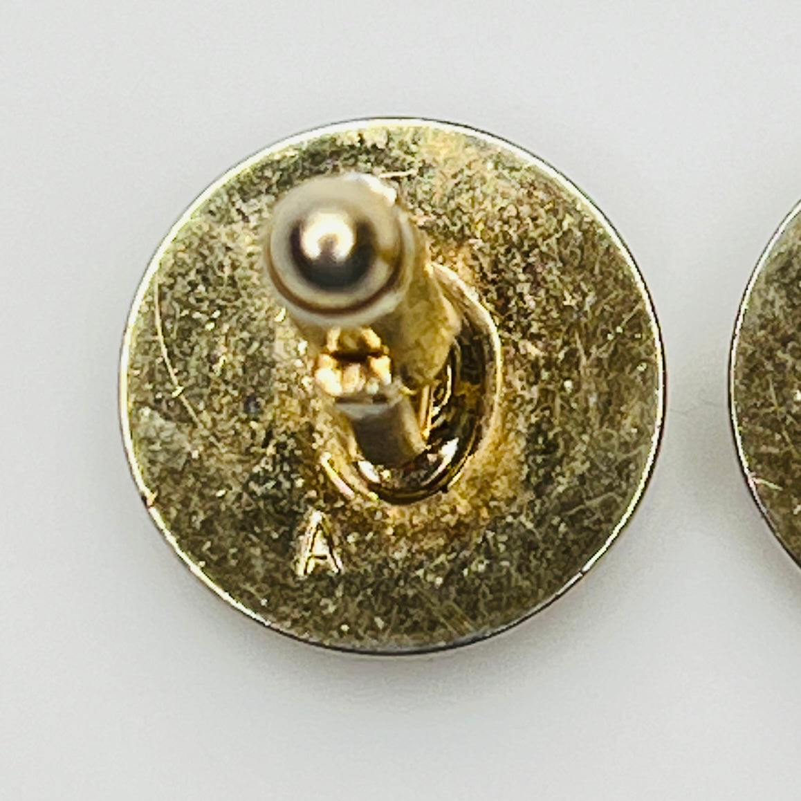Close-up of cufflink backs stamped with A (likely Anson)