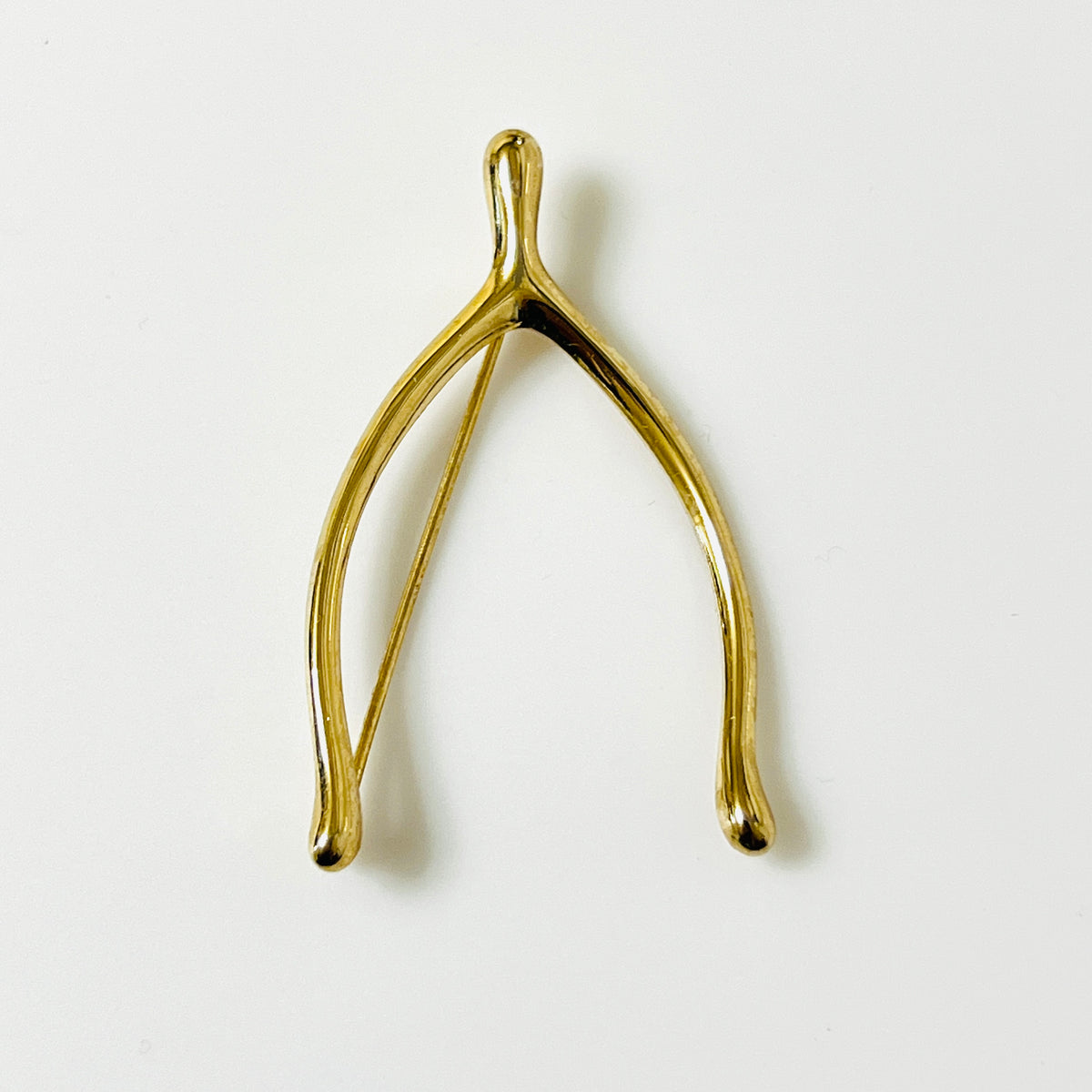 Vintage Napier gold-tone wishbone brooch with polished curved branches and softly rounded tips.