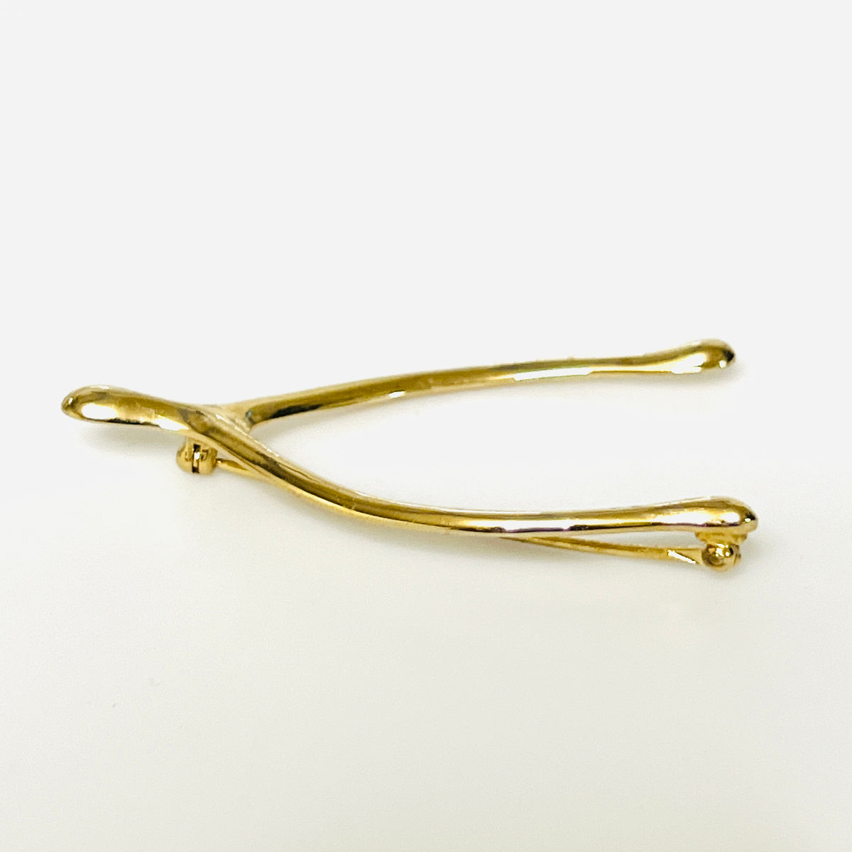 Angled view of the Napier wishbone brooch showing its rounded profile and polished gold-tone finish.