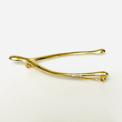 Angled view of the Napier wishbone brooch showing its rounded profile and polished gold-tone finish.