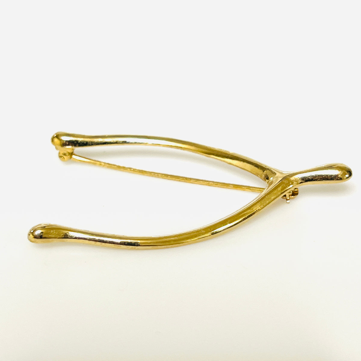 Angled view of the Napier wishbone brooch showing its rounded profile and polished gold-tone finish.