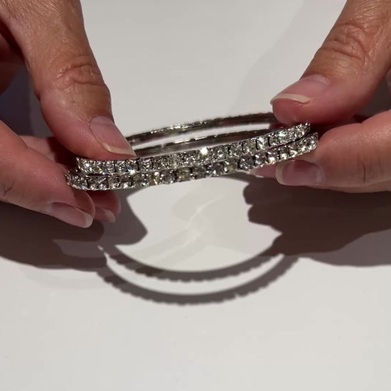 Set of two silver-tone bangle bracelets with prong-set clear rhinestones, vintage 1980s.