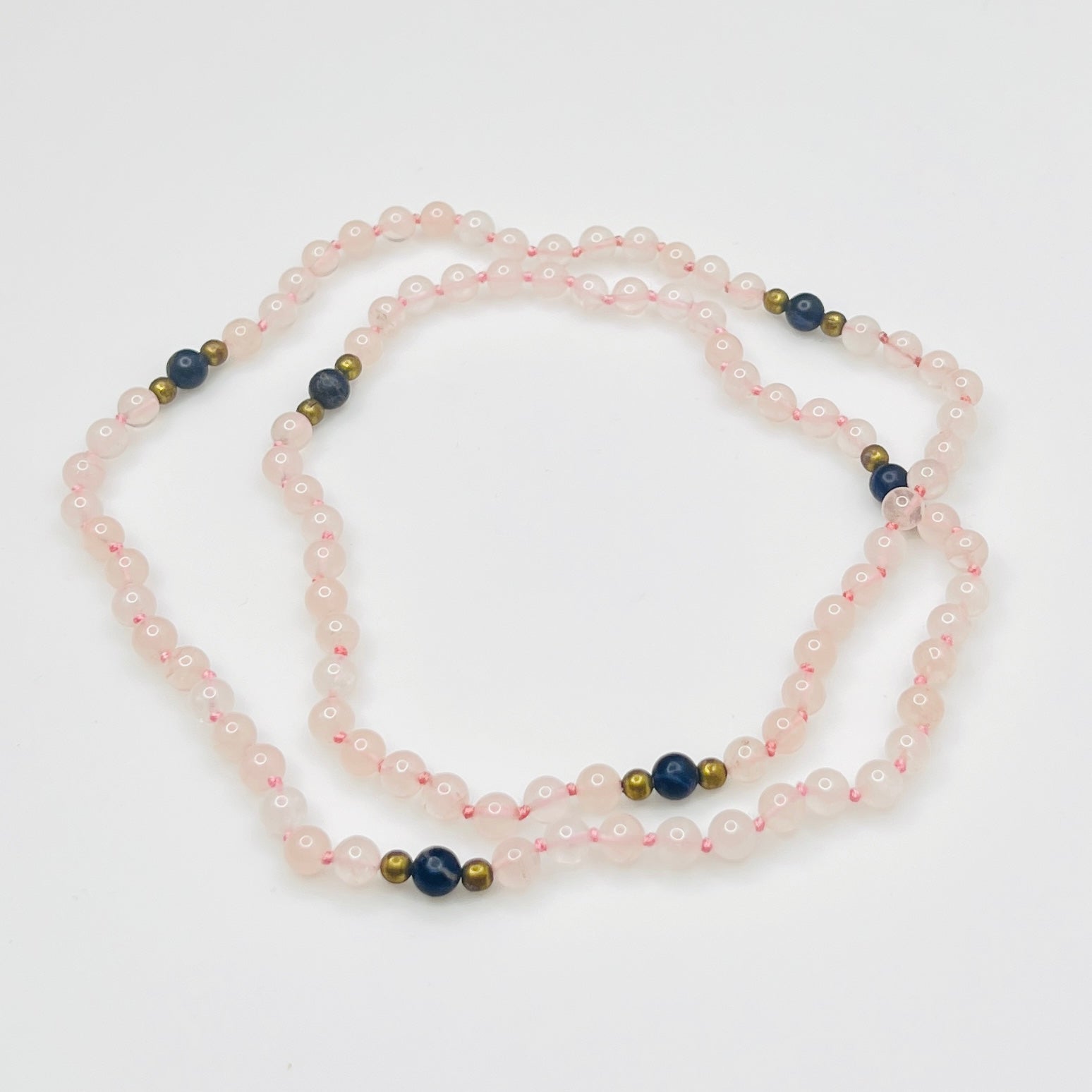 Long artisan rose quartz necklace on display form