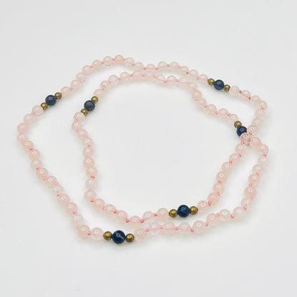 Long artisan rose quartz necklace on display form