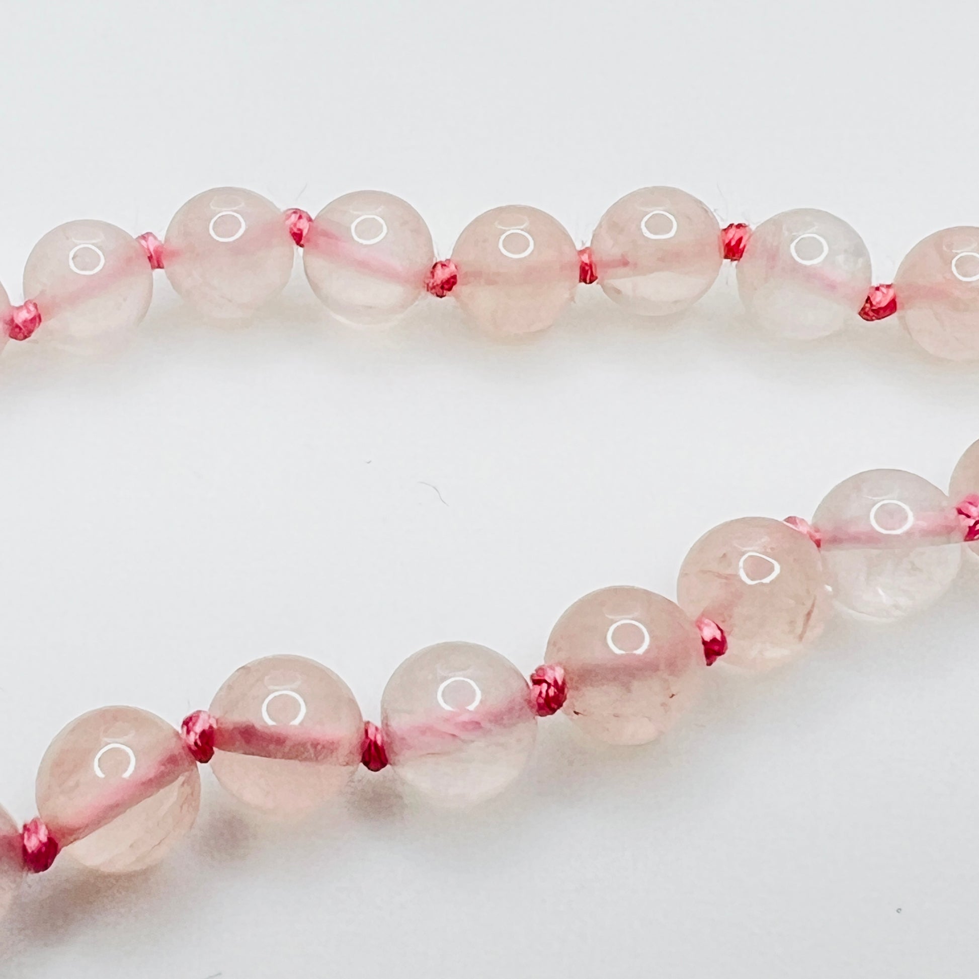 Close up of lapis and brass spacer beads with pink knotting