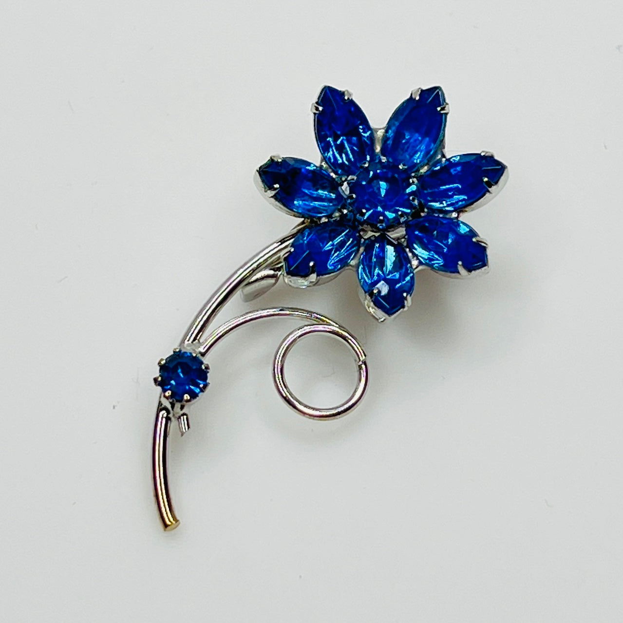 Vintage blue rhinestone flower brooch with silver-tone swirl stem – front view
