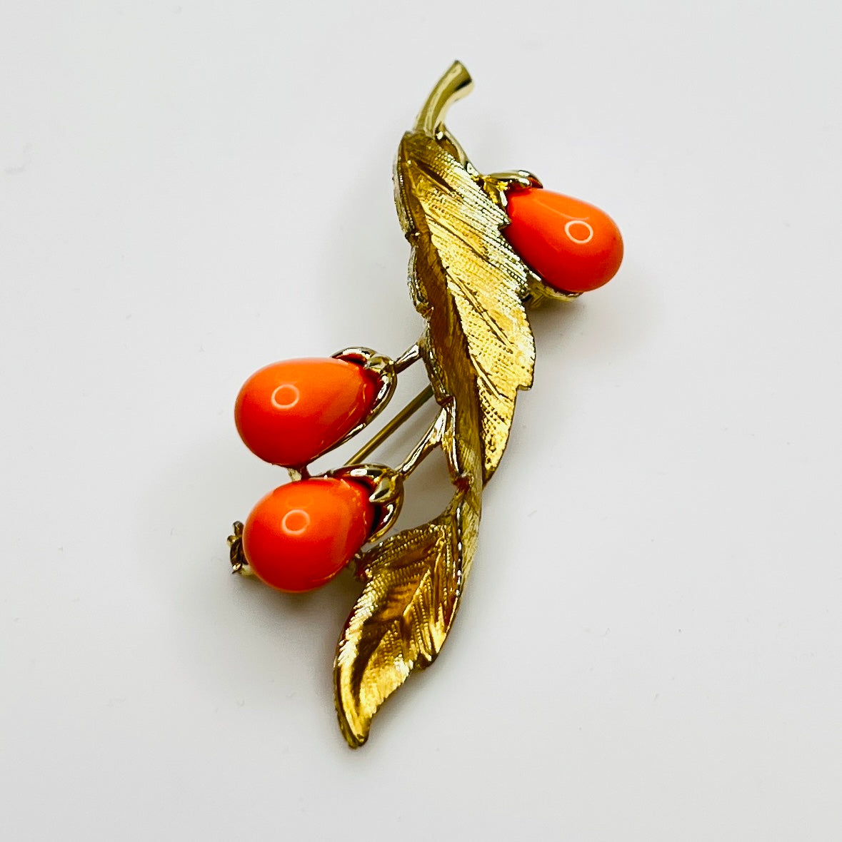 Angled side view of vintage brooch showing dimension and leaf texture