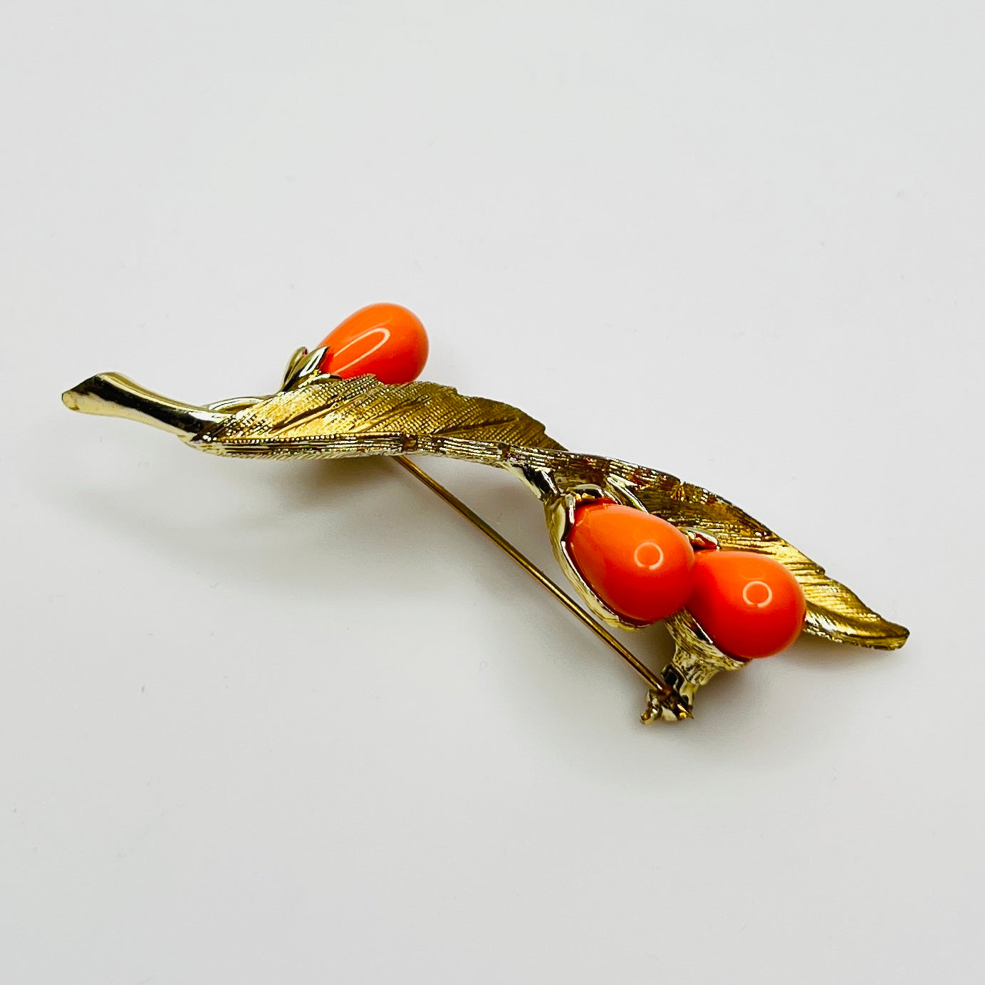 Angled side view of vintage brooch showing dimension and leaf texture