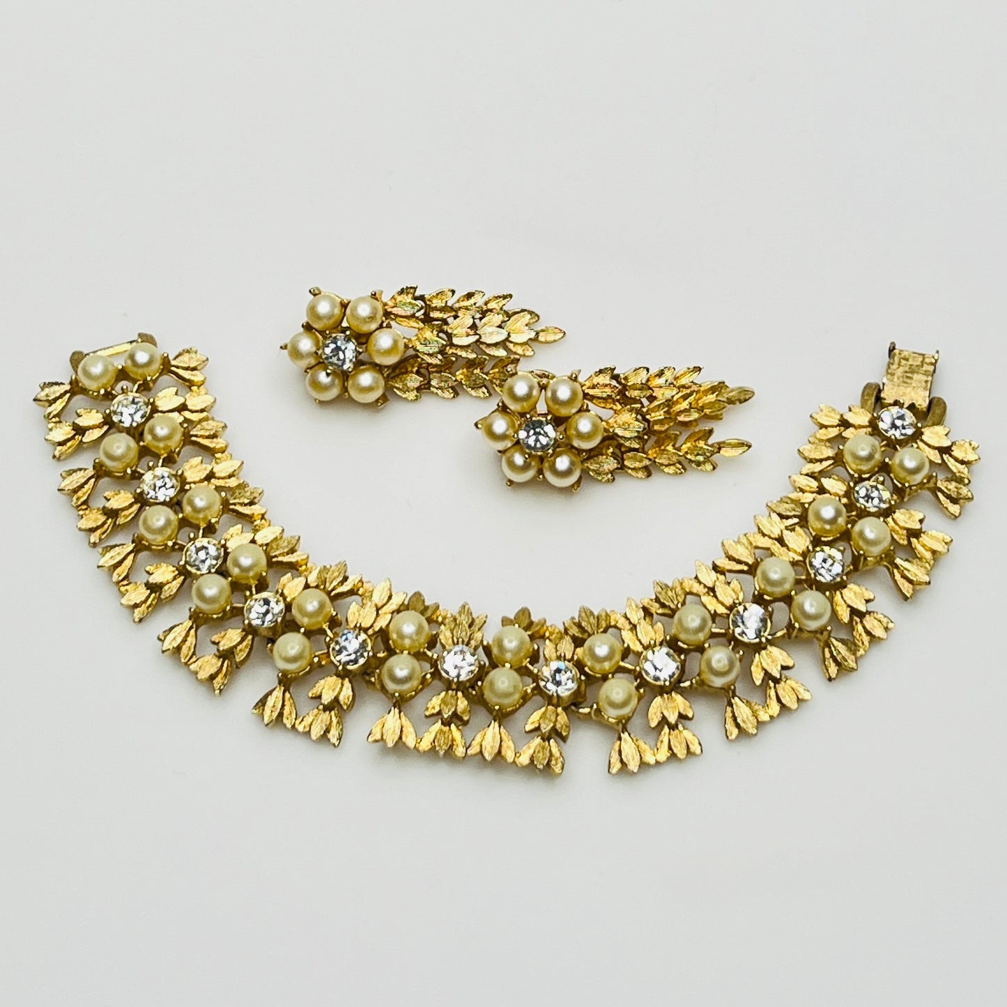 Vintage Sarah Coventry gold-tone bracelet and clip-on earrings with faux pearls and rhinestones.