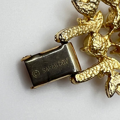 Gold bracelet with 'SARAH COV' clasp on a white background