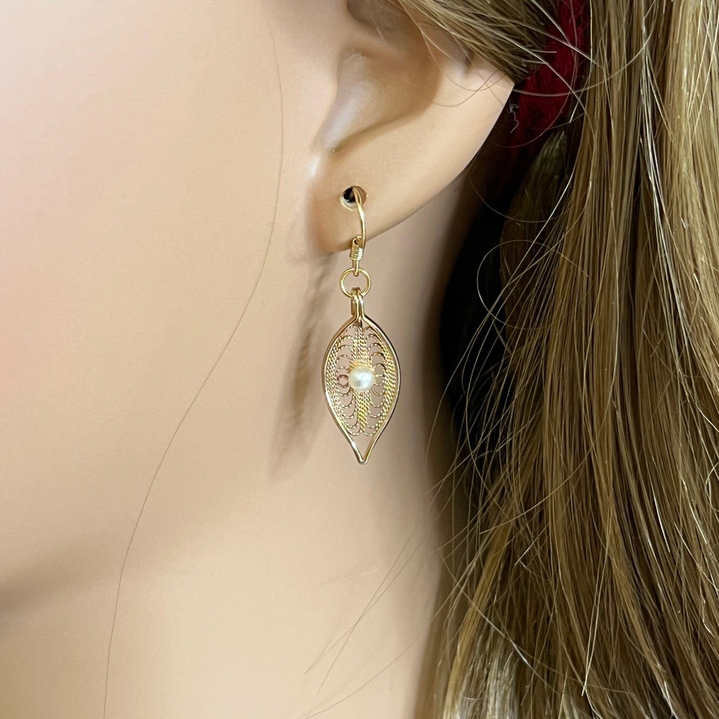 Close-up of gold-tone openwork earrings featuring pearl centers