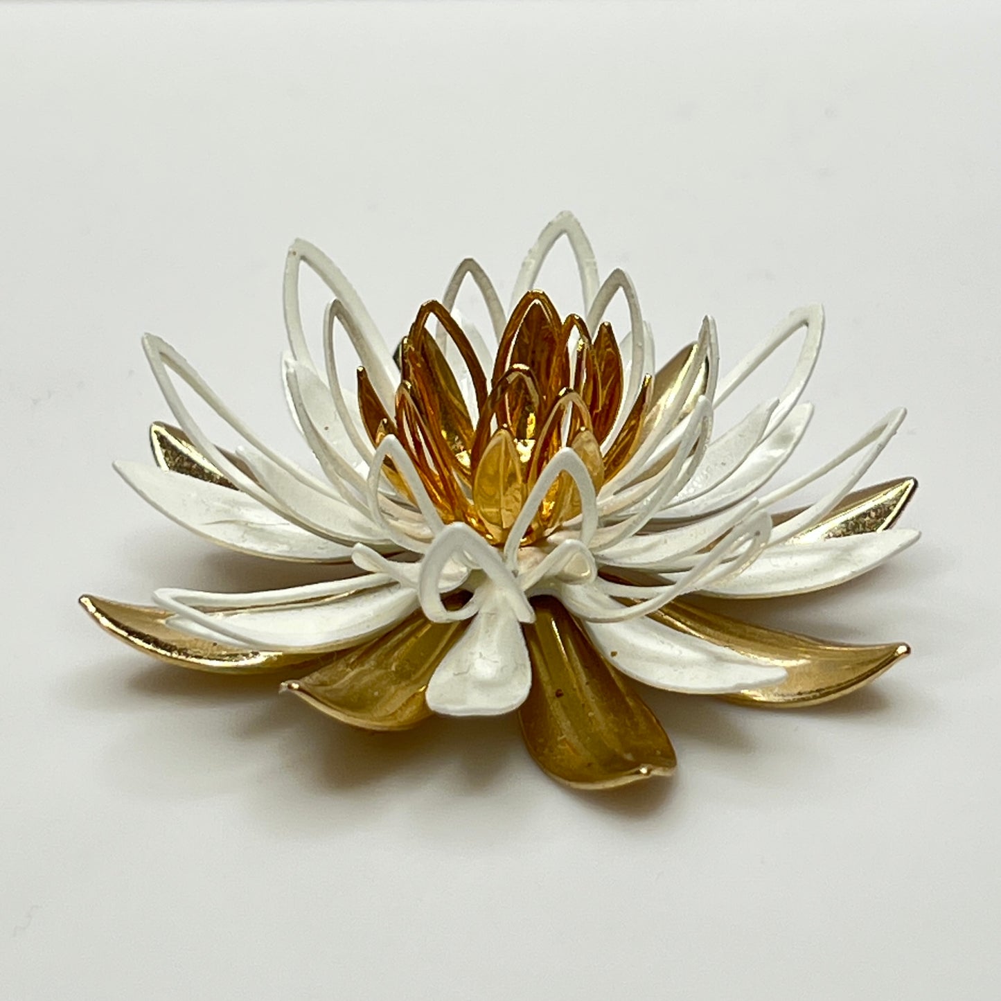 Close-up of white and gold enamel water lily brooch with layered petals