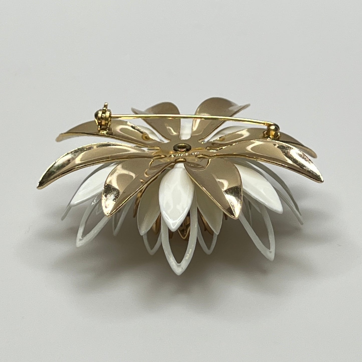 Close-up of white and gold enamel water lily brooch with layered petals