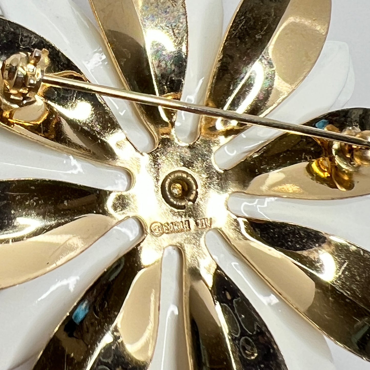 Close-up of white and gold enamel water lily brooch with layered petals