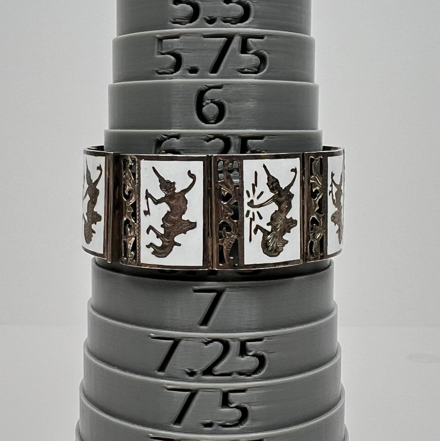 Close-up of white enamel bracelet with Thai goddess motifs