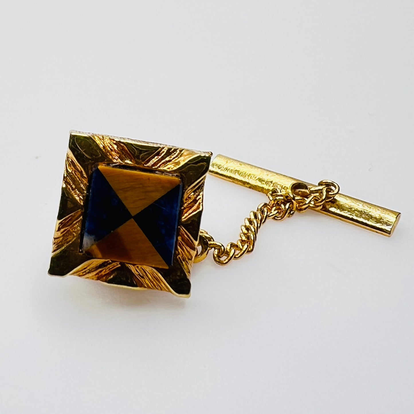 Close-up of Karatclad gold tie pin with lapis lazuli and tiger's eye stone inlay