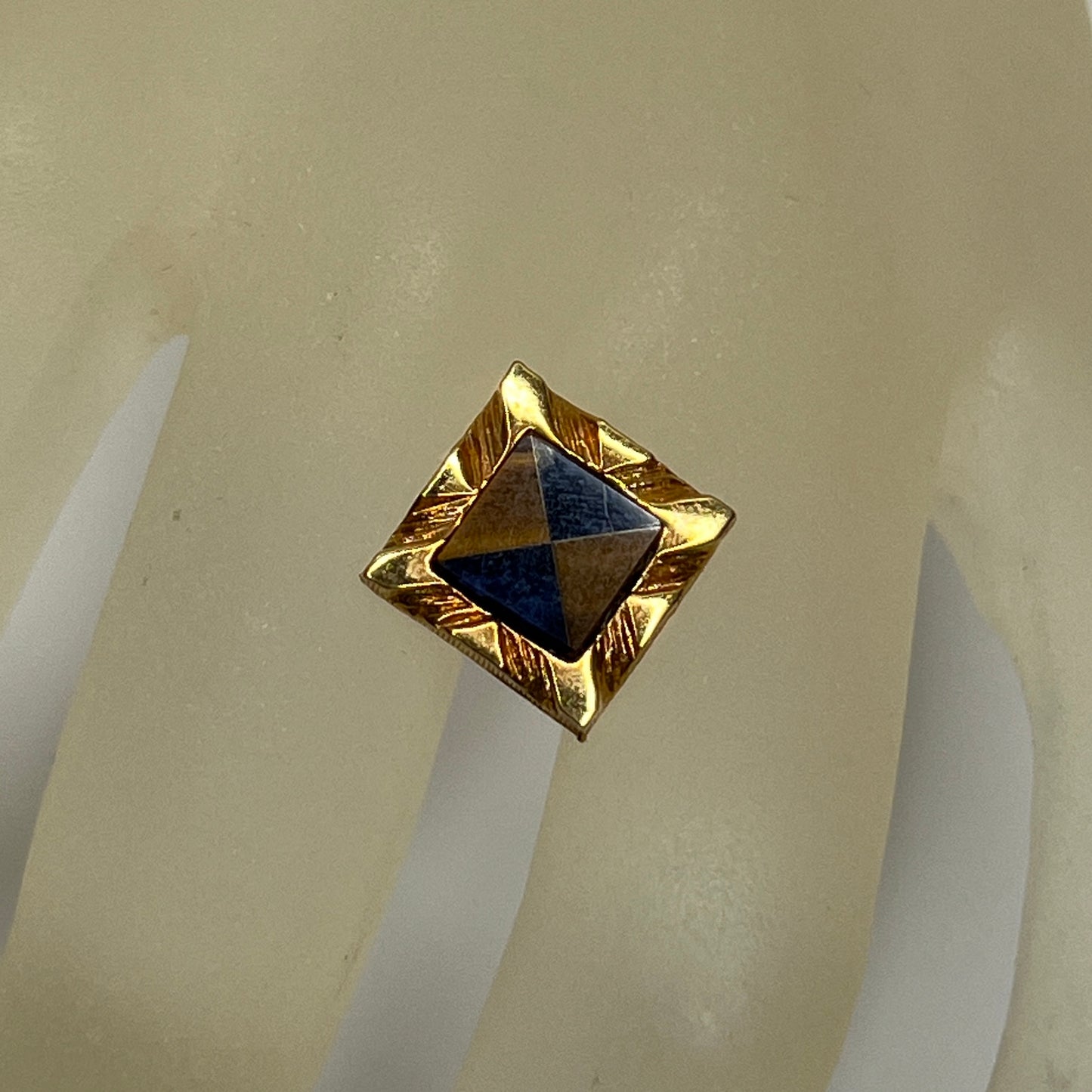 Close-up of Karatclad gold tie pin with navy and brown stone inlay