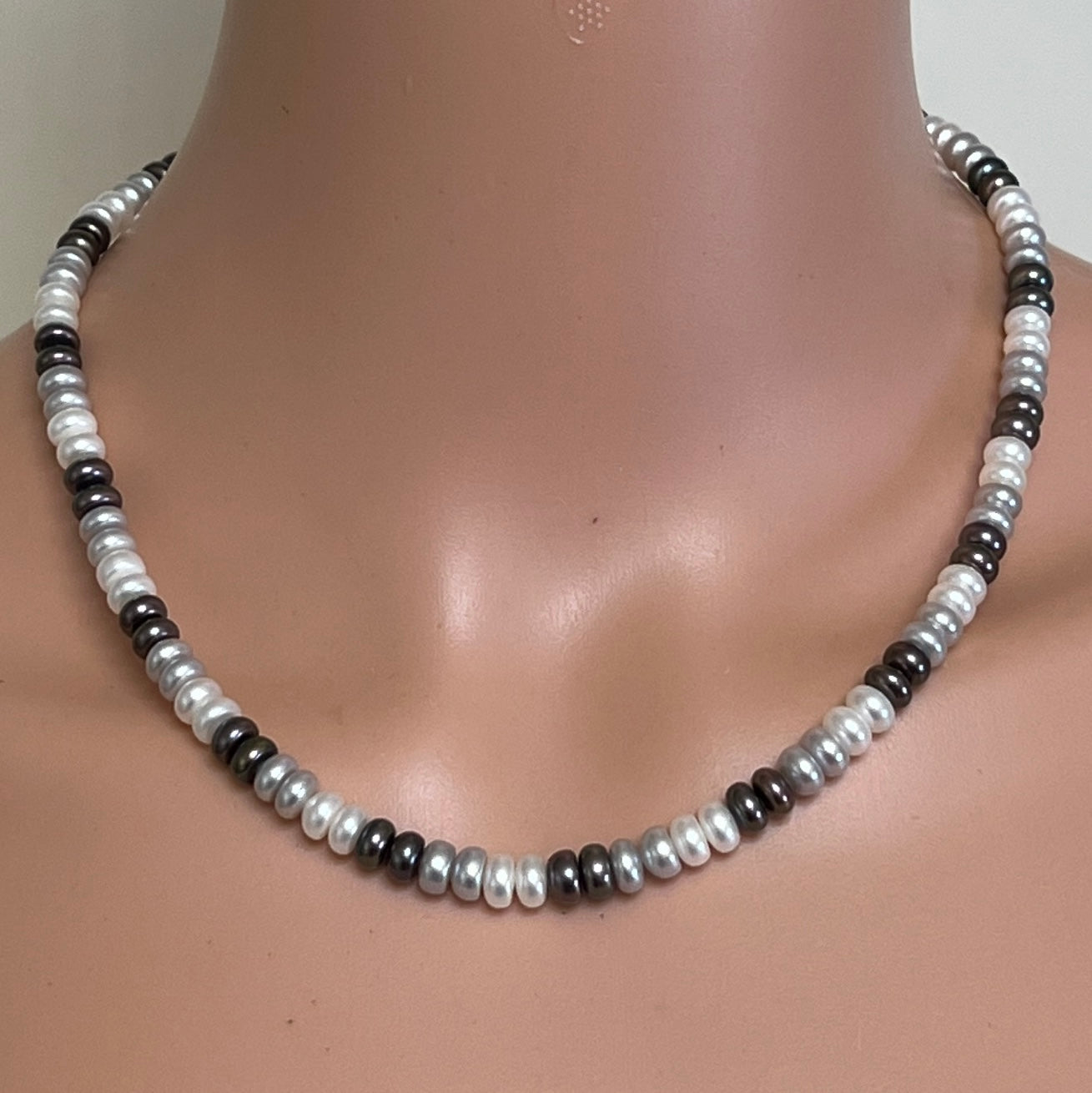 Tri-color cultured pearl necklace worn on mannequin with alternating white, grey, and black pearls