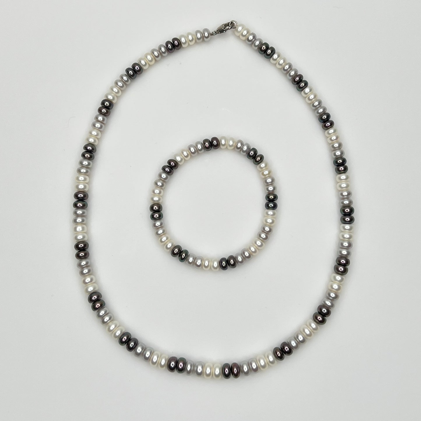 Close-up of matching pearl necklace and stretch bracelet in modern neutral tones