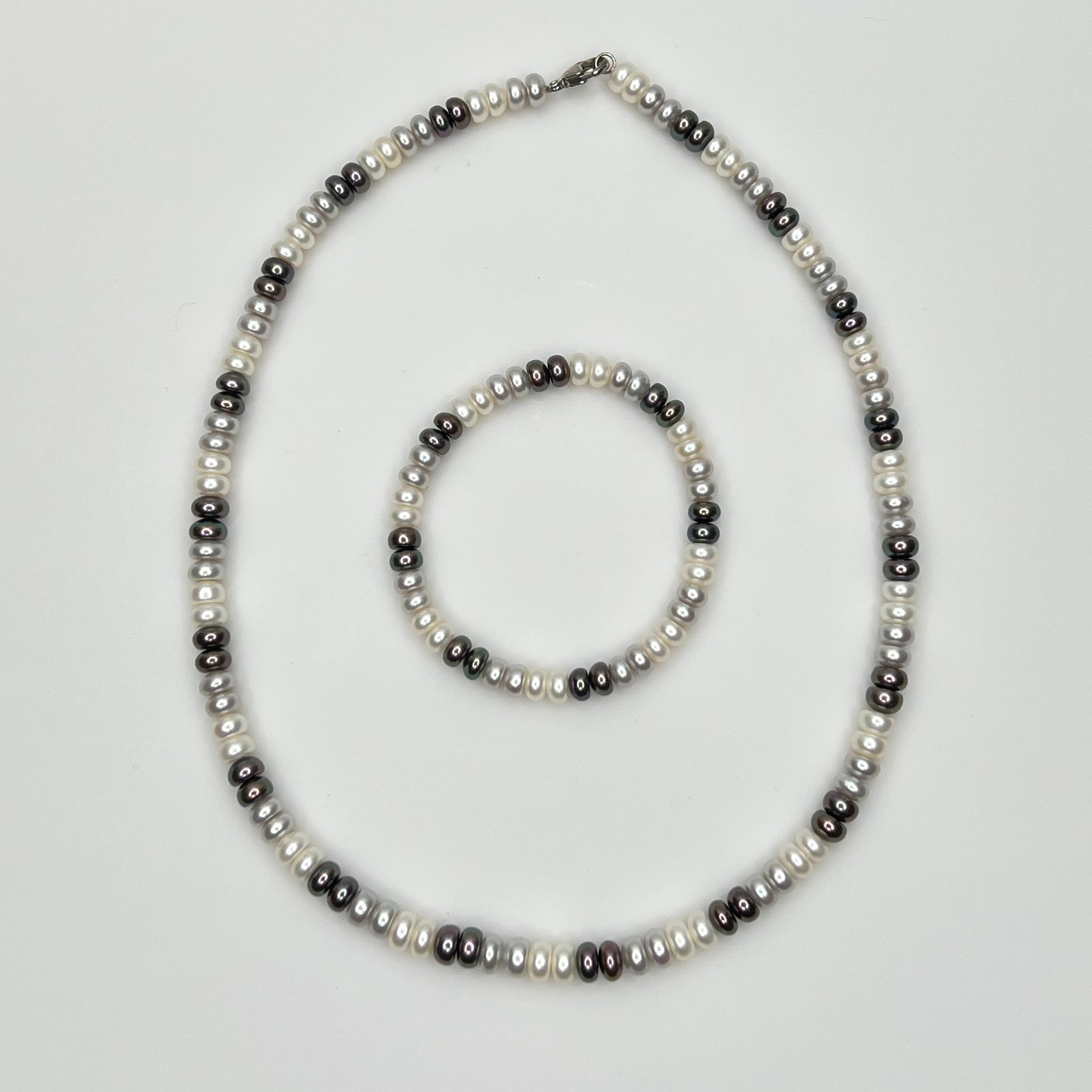 Close-up of matching pearl necklace and stretch bracelet in modern neutral tones