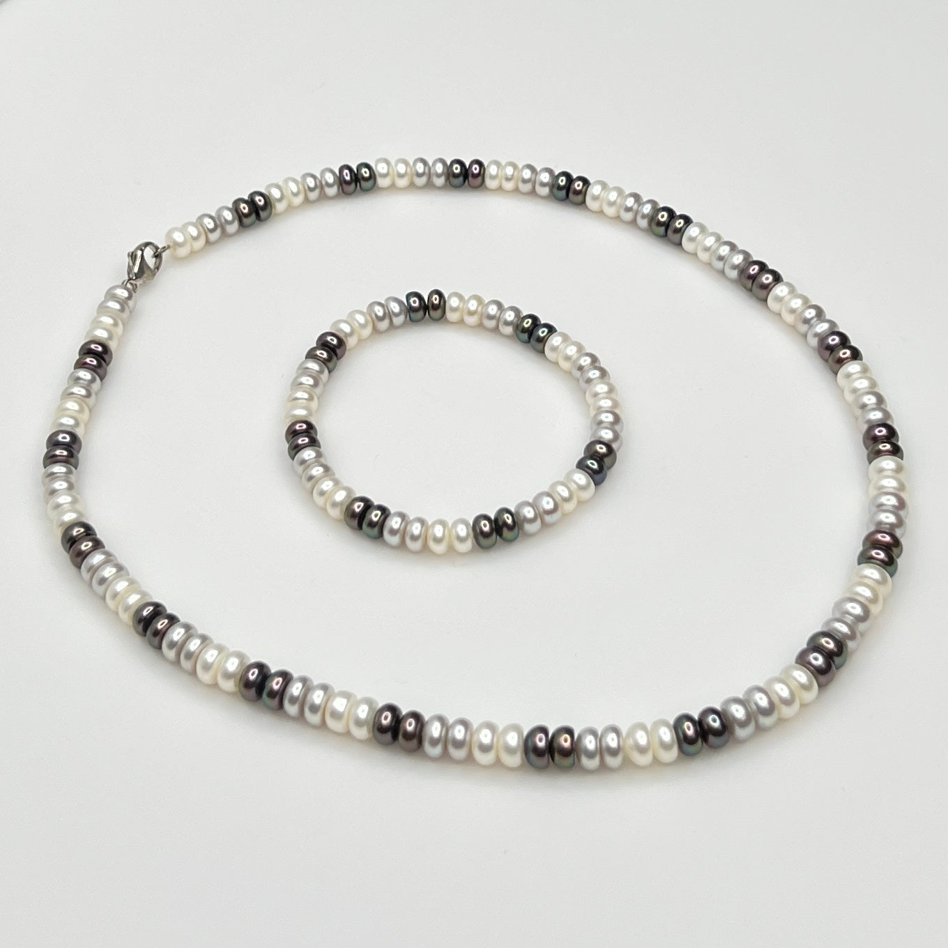 Close-up of matching pearl necklace and stretch bracelet in modern neutral tones