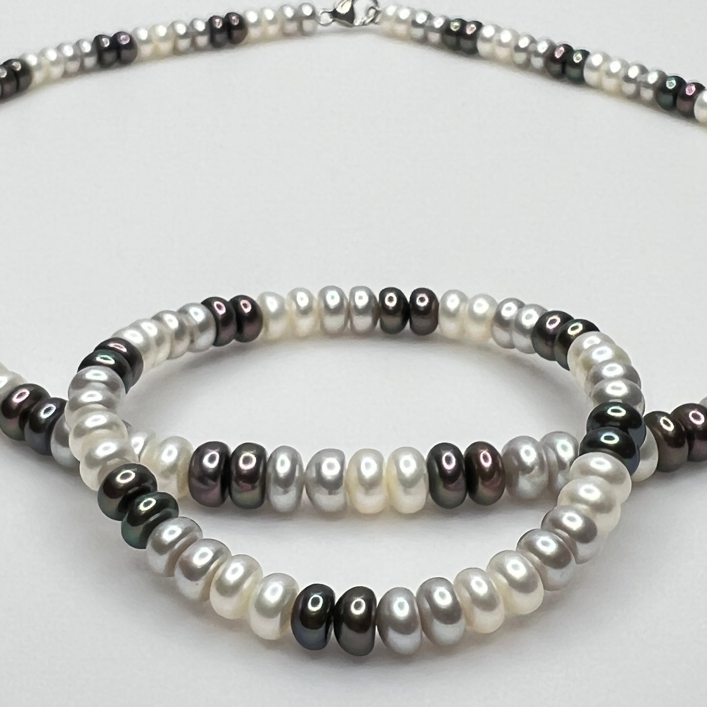 Close-up of matching pearl necklace and stretch bracelet in modern neutral tones