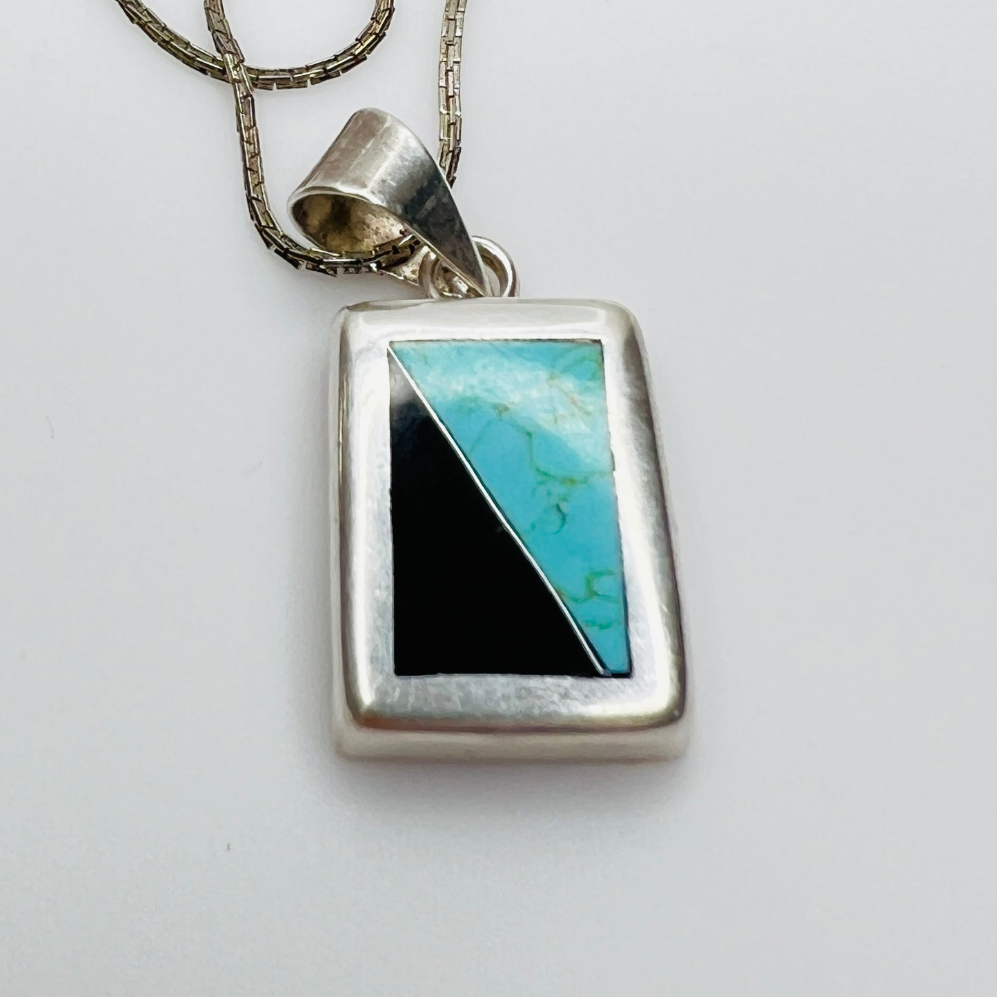 Detail of sterling pendant with turquoise and black onyx inlay