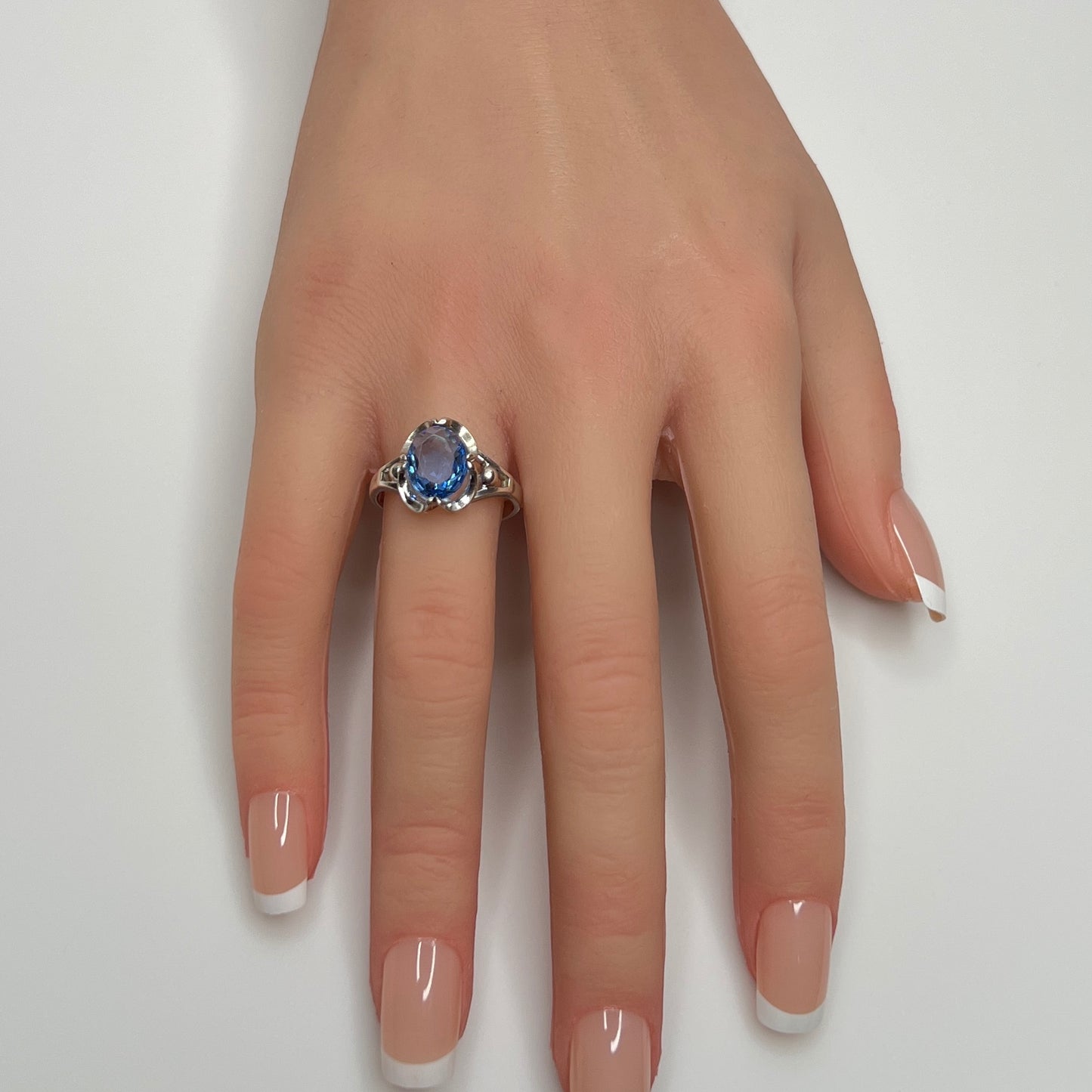 Sterling silver ring with oval blue topaz worn on hand